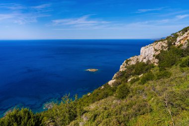 Kıbrıs Rum Kesimi, Amoros Çeşmesi 'ndeki güzel kıyı manzarası. Mavi denizin ortasında küçük bir ada tenha bir güzellik ortamı yaratır. Seyahat, tatil
