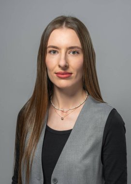 Tarafsız arka planda makyajlı genç bir kadının profesyonel stüdyo portresi. Model, kendinden emin ve rahat bir yüz ifadesiyle poz verir. Güzellik ve rahat stil kavramı.