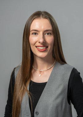 Stüdyo ortamında gülümseyen çekici genç bir kadın. Minimalist zemin, kendinden emin ifadesini ve doğal güzelliğini vurguluyor..