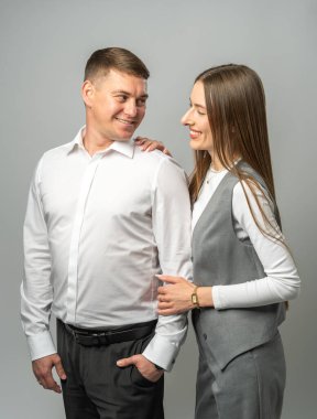 Stüdyodaki gülümseyen genç çift birbirlerine sevgi ve sıcaklıkla bakıyor. Şık giyinmiş kız ve erkek. Romantizm, güven ve duygusal bağ kavramı.