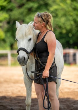 Genç ahır işçisi beyaz ata nazikçe dokunuyor, dizginlerini nazikçe tutuyor. İnsan ve hayvan arasındaki duygusal bağ. Önemseme, sevgi, güven ve huzurlu kırsal yaşam kavramı.
