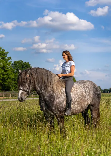 Yeşil çim tarlasında çıplak oturan bir kız. Doğal ışık, sakin kırsal atmosfer, insan ve hayvan arasındaki özgürlüğü, güveni ve uyumu simgeliyor..