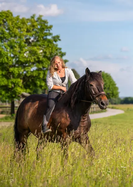 Eyeri olmayan at sırtında bir kadın kırsalda sessiz bir yolda. Huzurlu bir yaz günü doğayla, özgürlükle ve kırsal yaşam tarzıyla bütünlüğünü ifade ediyor..