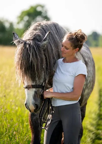 Genç bir kadın sessiz bir kırsal şeritte dururken gri atını sevgiyle kucaklıyor. İnsanla hayvan arasındaki duygusal bağı yakalayan dokunaklı bir an..