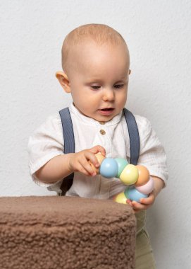 Ev ortamında oyuncaklarla oynayan sevimli bir yaşında bir erkek bebek. Erken çocukluk, öğrenme ve keşfin samimi anı.