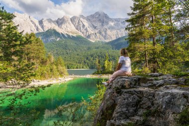 Gezgin kadın Eibsee Gölü 'ne ve kayalık açıdan Bavyera Alplerine hayranlık duyuyor. Almanya 'da huzurlu bir manzara, yürüyüş, doğa ve seyahat temaları için harika..