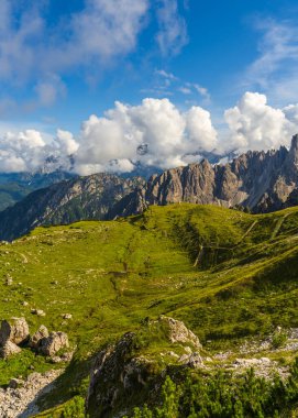 Dolomite Alpleri 'nin engebeli arazisinde berrak gökyüzü ve yumuşak bulutların karışımıyla dağ yürüyüşü yolları nefes kesici. Yürüyüş ve manzara fotoğrafçılığı için mükemmel..