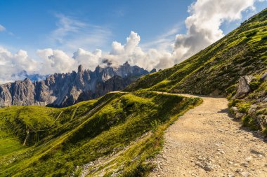 Dolomitlerdeki Drei Zinnen 'in ikonik tepelerinden geçen dağlık patikalar. Etrafı dramatik dağlar ve doğal güzelliklerle çevrili doğa, macera ve turizm temaları için ideal..