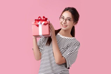 Mutlu gençler pembe arka planda hediye kutularıyla mutlu olurlar.