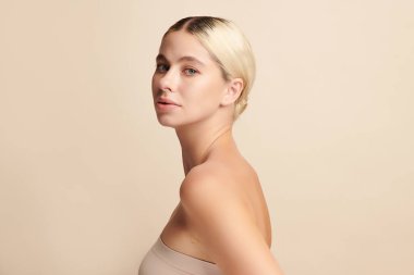 Bej arkaplan, yüz bakımı, yüz bakımı, kozmetoloji, güzellik ve kaplıca gibi temiz cilde sahip güzel genç bir kadın., 