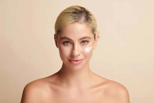 Hermosa Joven Aplicación Crema Facial Sobre Fondo Beige Cuidado Cara — Foto de Stock