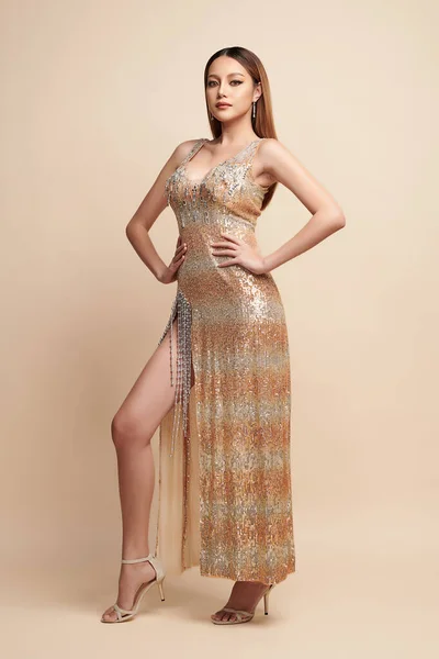 Beautiful young asian woman, with gold Dress, Elegant Woman in Sexy Evening Gown, Beautiful on beige Background,