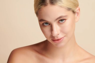 Bej arkaplan, yüz bakımı, yüz bakımı, kozmetoloji, güzellik ve kaplıca gibi temiz cilde sahip güzel genç bir kadın.,