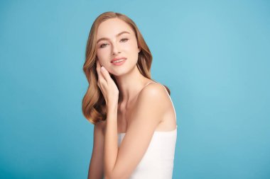 Mavi arka planda taze cildi temiz genç bir kadın, yüz bakımı, yüz bakımı, kozmetoloji, güzellik ve kaplıca, kadın portresi.