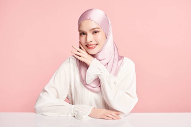 Pembe arka planda pembe tesettürlü güzel Asyalı Müslüman kadın, Arap Güzelliği Portresi.