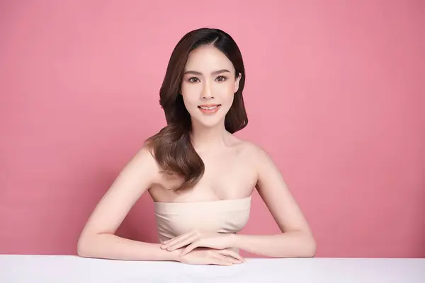 年轻美丽的亚洲女人 皮肤清澈 粉红背景 面部护理 面部护理 美容美发 亚洲女性肖像 图库图片