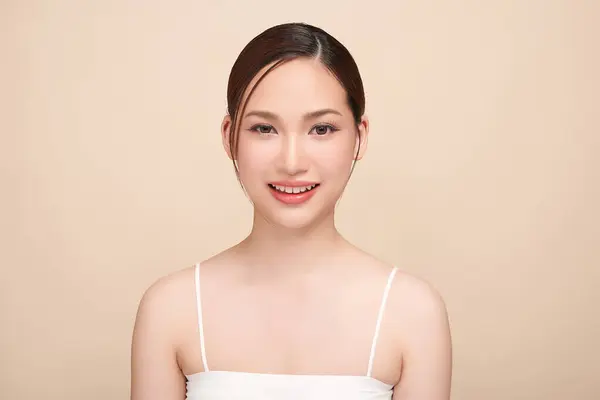 美丽的年轻亚洲女人 有着米色背景 面部护理 面部治疗 美容美发 亚洲女性肖像等洁白新鲜的肌肤 图库图片