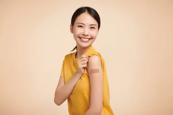 Junge Asiatische Frauen Lächeln Nach Der Impfung Halten Den Hemdsärmel lizenzfreie Stockbilder