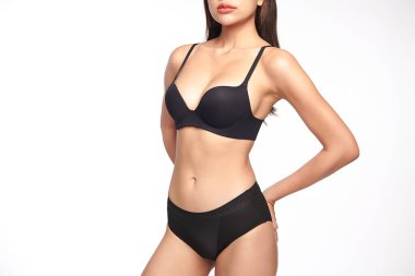 Beyaz arka planda siyah iç çamaşırlarıyla poz veren kendinden emin, genç Asyalı bir kadın.,