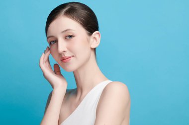 Mavi arka planda taze cildi temiz genç bir kadın, yüz bakımı, yüz bakımı, kozmetoloji, güzellik ve kaplıca, kadın portresi.