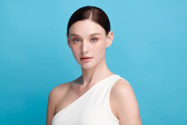 Mavi arka planda taze cildi temiz genç bir kadın, yüz bakımı, yüz bakımı, kozmetoloji, güzellik ve kaplıca, kadın portresi.