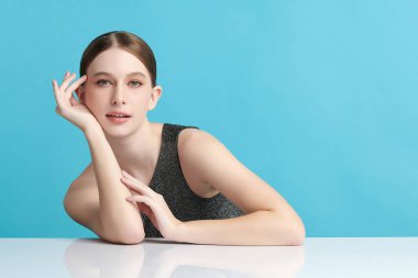 Mavi arka planda taze cildi temiz genç bir kadın, yüz bakımı, yüz bakımı, kozmetoloji, güzellik ve kaplıca, kadın portresi.