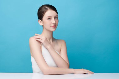 Mavi arka planda taze cildi temiz genç bir kadın, yüz bakımı, yüz bakımı, kozmetoloji, güzellik ve kaplıca, kadın portresi.