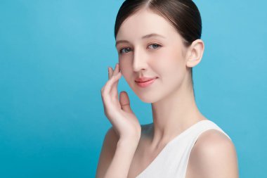 Mavi arka planda taze cildi temiz genç bir kadın, yüz bakımı, yüz bakımı, kozmetoloji, güzellik ve kaplıca, kadın portresi.