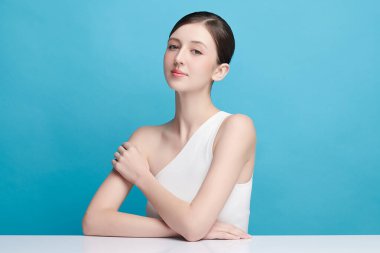 Mavi arka planda taze cildi temiz genç bir kadın, yüz bakımı, yüz bakımı, kozmetoloji, güzellik ve kaplıca, kadın portresi.