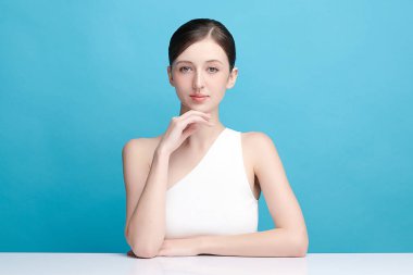 Mavi arka planda taze cildi temiz genç bir kadın, yüz bakımı, yüz bakımı, kozmetoloji, güzellik ve kaplıca, kadın portresi.