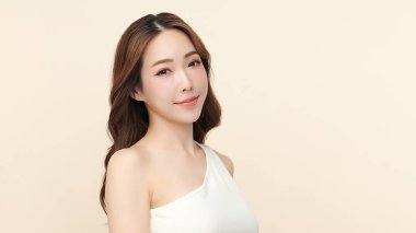 Güzel, genç bir Asyalı kadın, bej bir arka planda temiz, taze bir ten. Cilt bakımı, yüz bakımı, kozmetoloji, güzellik ve kaplıca. Asyalı bir kadının zarif bir portresi..