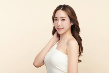 Güzel, genç bir Asyalı kadın, bej bir arka planda temiz, taze bir ten. Cilt bakımı, yüz bakımı, kozmetoloji, güzellik ve kaplıca. Asyalı bir kadının zarif bir portresi..