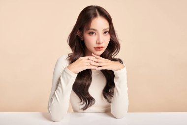 Güzel, genç bir Asyalı kadın, bej bir arka planda temiz, taze bir ten. Cilt bakımı, yüz bakımı, kozmetoloji, güzellik ve kaplıca. Asyalı bir kadının zarif bir portresi..