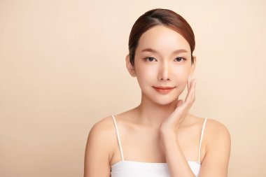 Güzel, genç bir Asyalı kadın, bej bir arka planda temiz, taze bir ten. Cilt bakımı, yüz bakımı, kozmetoloji, güzellik ve kaplıca. Asyalı bir kadının zarif bir portresi..