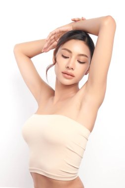 Güzel genç Asyalı kadın, beyaz bir arka plan, pürüzsüz bir koltuk altı temizliği ve korunma kavramına karşı ellerini kaldırıyor.