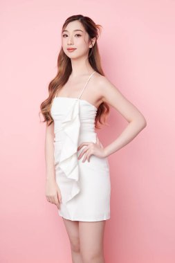 Seksi elbiseli güzel Asyalı bir kadının güzel yüzü pembe arka planda kusursuz ince vücut estetik cerrahi estetik estetik estetik, yüz bakımı ve cilt bakımı konsepti.