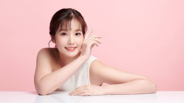 Pembe arka planda, temiz ve taze bir teni olan güzel bir Asyalı kadın. Cilt bakımı, yüz bakımı, kozmetoloji, güzellik ve kaplıca. Asyalı bir kadının zarif bir portresi..