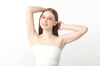 Güzel genç kadın, beyaz bir arka plan, pürüzsüz bir koltuk altı temizliği ve korunma kavramına karşı ellerini kaldırır ve temiz ve hijyenik bir şekilde ellerini kaldırır.