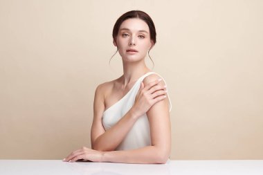 Bej bir arka planda temiz, taze bir teni olan güzel bir genç kadın. Cilt bakımı, yüz bakımı, kozmetoloji, güzellik ve kaplıca. Bir kadının zarif bir portresi..