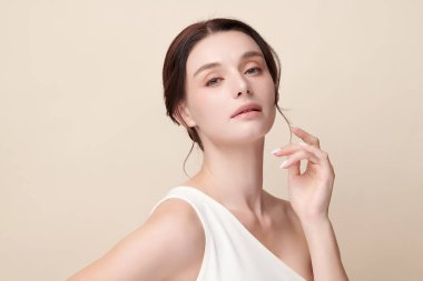 Bej bir arka planda temiz, taze bir teni olan güzel bir genç kadın. Cilt bakımı, yüz bakımı, kozmetoloji, güzellik ve kaplıca. Bir kadının zarif bir portresi..