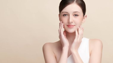 Bej bir arka planda temiz, taze bir teni olan güzel bir genç kadın. Cilt bakımı, yüz bakımı, kozmetoloji, güzellik ve kaplıca. Bir kadının zarif bir portresi..