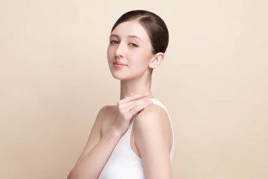 Bej bir arka planda temiz, taze bir teni olan güzel bir genç kadın. Cilt bakımı, yüz bakımı, kozmetoloji, güzellik ve kaplıca. Bir kadının zarif bir portresi..