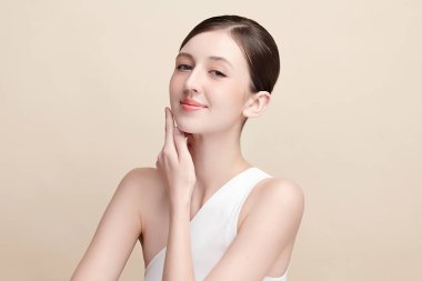 Bej bir arka planda temiz, taze bir teni olan güzel bir genç kadın. Cilt bakımı, yüz bakımı, kozmetoloji, güzellik ve kaplıca. Bir kadının zarif bir portresi..