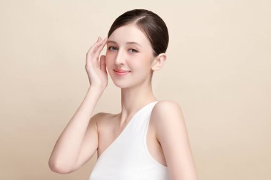 Bej bir arka planda temiz, taze bir teni olan güzel bir genç kadın. Cilt bakımı, yüz bakımı, kozmetoloji, güzellik ve kaplıca. Bir kadının zarif bir portresi..