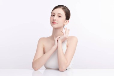 Beyaz bir arka planda temiz, taze bir teni olan güzel bir genç kadın. Cilt bakımı, yüz bakımı, kozmetoloji, güzellik ve kaplıca. Bir kadının zarif bir portresi..