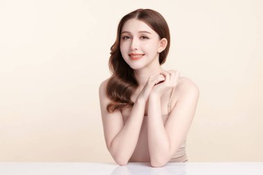 Güzel, genç bir Asyalı kadın, bej bir arka planda temiz, taze bir ten. Cilt bakımı, yüz bakımı, kozmetoloji, güzellik ve kaplıca. Asyalı bir kadının zarif bir portresi..