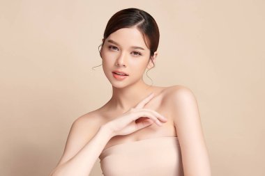 Güzel, genç bir Asyalı kadın, bej bir arka planda temiz, taze bir ten. Cilt bakımı, yüz bakımı, kozmetoloji, güzellik ve kaplıca. Asyalı bir kadının zarif bir portresi..