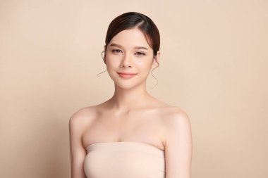 Güzel, genç bir Asyalı kadın, bej bir arka planda temiz, taze bir ten. Cilt bakımı, yüz bakımı, kozmetoloji, güzellik ve kaplıca. Asyalı bir kadının zarif bir portresi..