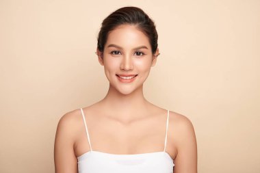 Güzel, genç bir Asyalı kadın, bej bir arka planda temiz, taze bir ten. Cilt bakımı, yüz bakımı, kozmetoloji, güzellik ve kaplıca. Asyalı bir kadının zarif bir portresi..