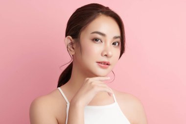Pembe arka planda, temiz ve taze bir teni olan güzel bir Asyalı kadın. Cilt bakımı, yüz bakımı, kozmetoloji, güzellik ve kaplıca. Asyalı bir kadının zarif bir portresi..